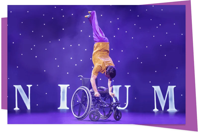 Omnium Circus performer Rik Daniels performing a handstand on a wheelchair